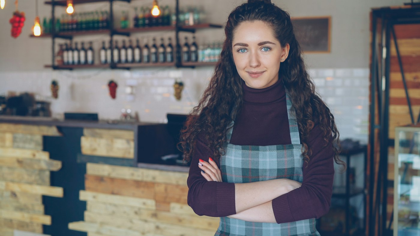 A smiling woman standing in her coffee shop.