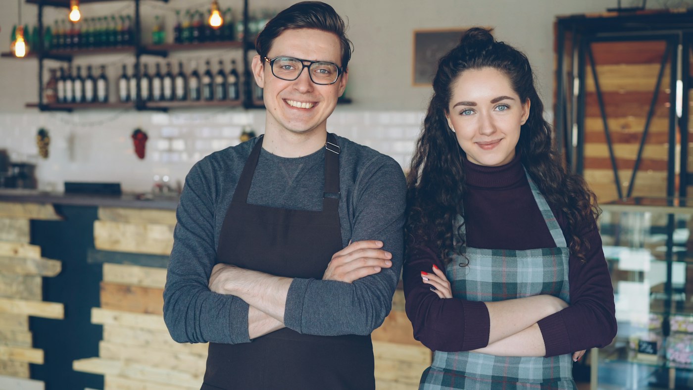 Two cafe owners standing together at their counter.