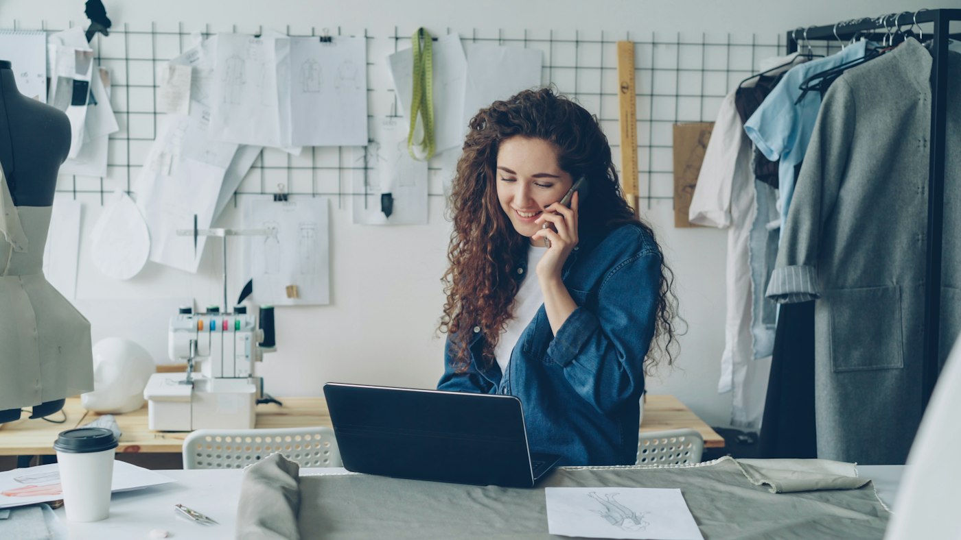 A designer working on a laptop and phone.