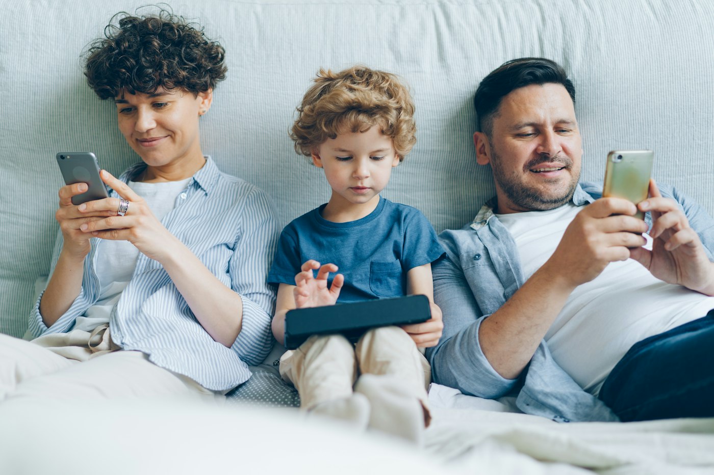 A family sitting on a sofa looking at a phone together.