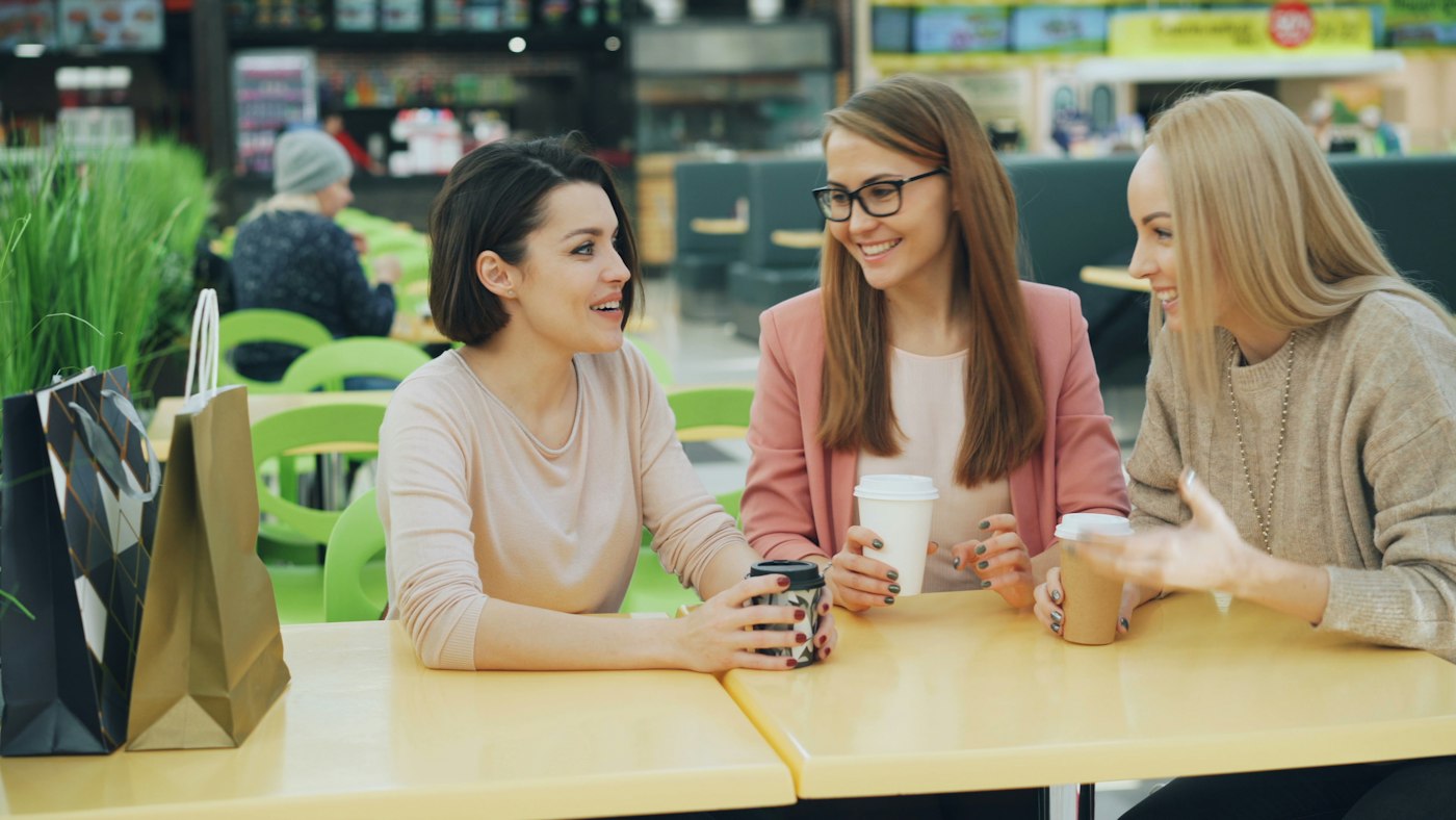 Three women talking at a cafe table.